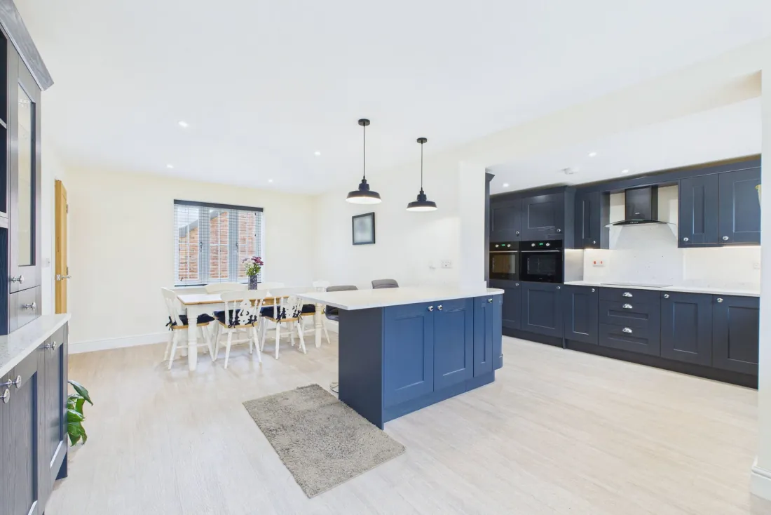 The double-aspect kitchen-diner wide, with navy cabinetry, Minerva peninsula and oak dining table