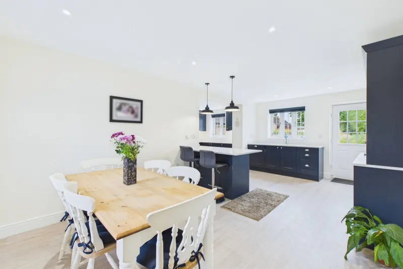 The dining end of the kitchen with oak table beneath industrial pendants and side window onto the garden