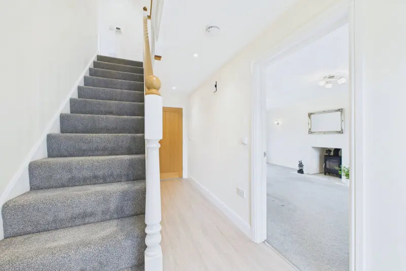 The entrance hallway with LVT flooring, oak internal doors and the staircase rising to the first floor
