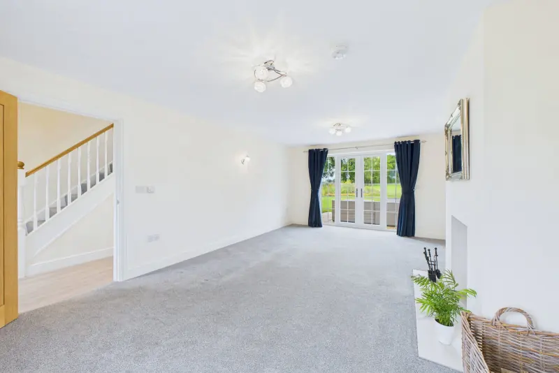 The lounge alternate angle, looking from the staircase entrance toward the log burner and twin patio doors