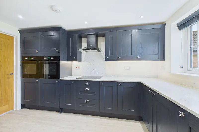 The kitchen detail, showing the inset induction hob, oven and chimney hood in deep navy