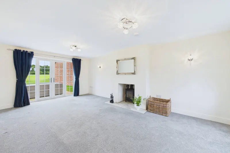 The lounge with the log burner on its tiled hearth and twin doors leading to the rear patio
