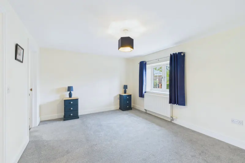 The principal bedroom, double-windowed and front-aspect, with neutral carpet and bedside cabinets
