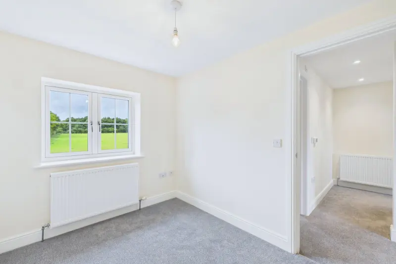 A first-floor bedroom with single rear-aspect window framing the open fields