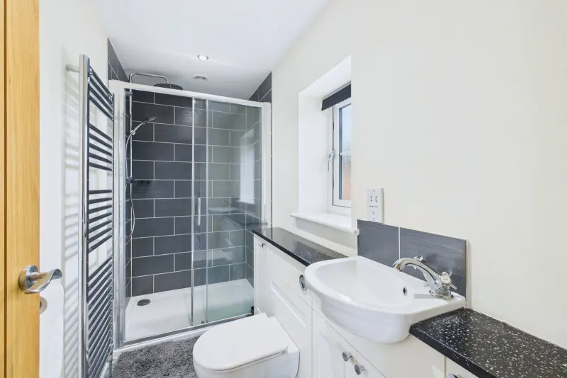 The principal en-suite shower room with walk-in shower, vanity unit and chrome towel rail