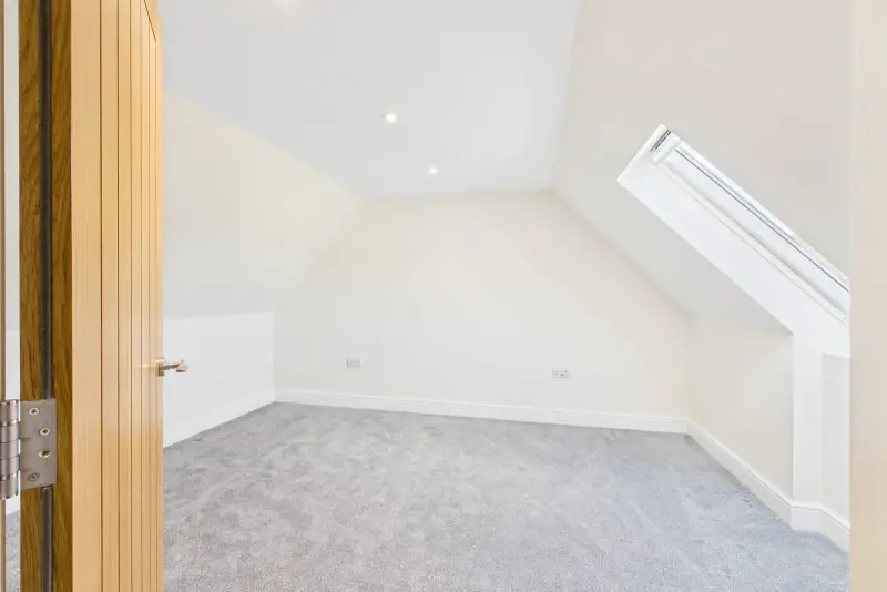 A second-floor bedroom with Velux window, sloped eaves and field views