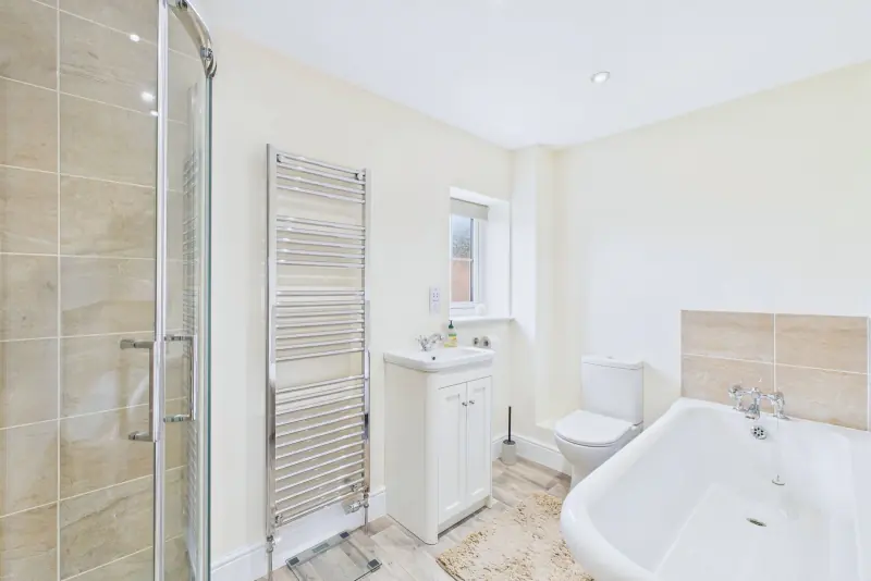 The family bathroom with a free-standing roll-top bath, walk-in corner shower and vanity unit
