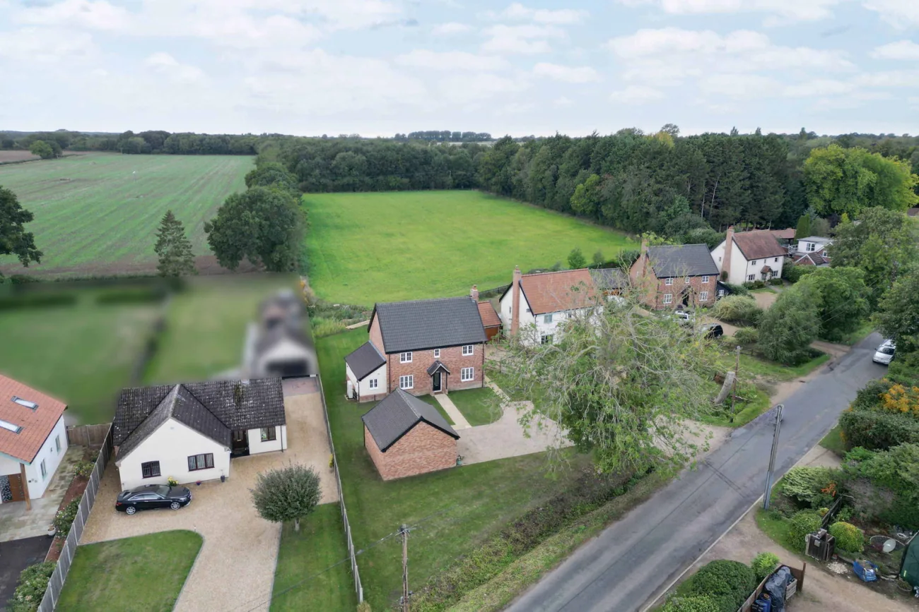 A wide drone view of the home set within the Norfolk plain, with neighbouring properties and open fields drawing east toward Attleborough