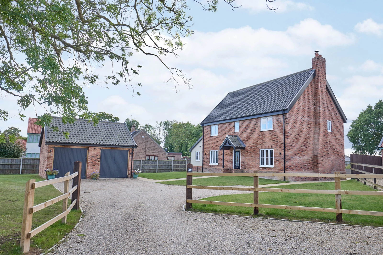 The front elevation of the home at Long Street, brick-built with white-painted porch and tiled roof, the detached double garage to the left