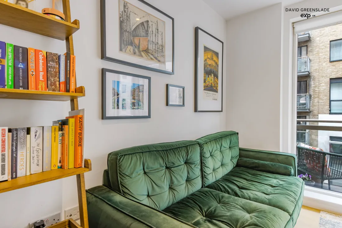 The living area with a green sofa and gallery wall