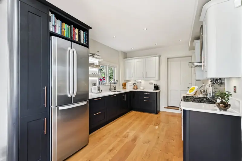 The kitchen island with bar stools and dark cabinetry