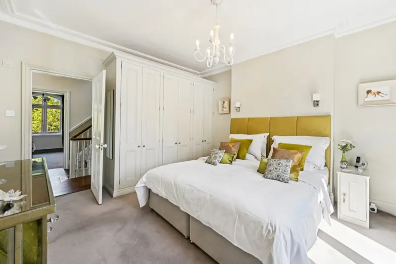 The principal bedroom, with grass-cloth wallpaper and a tailored upholstered headboard