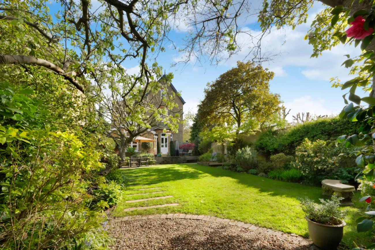 The walled rear garden with mature planting and lawn
