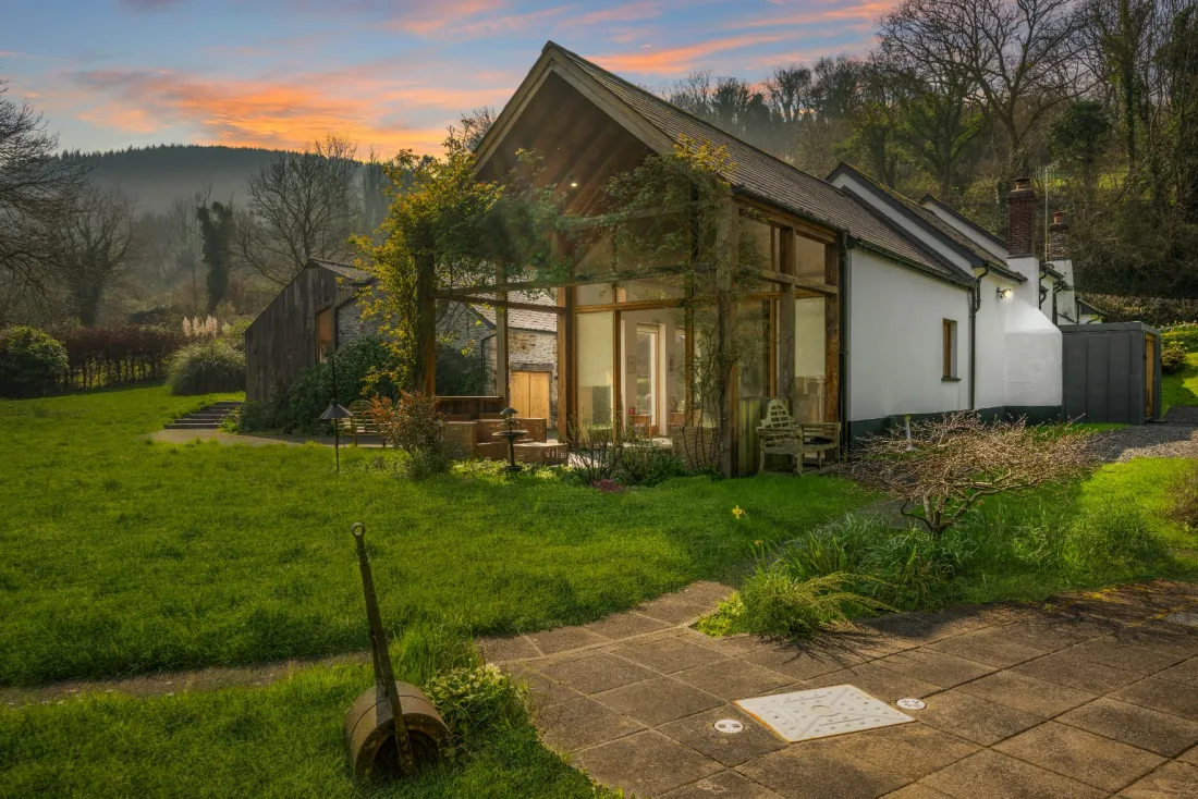 Lower Rowes Farm at twilight — glass extension lit against the valley