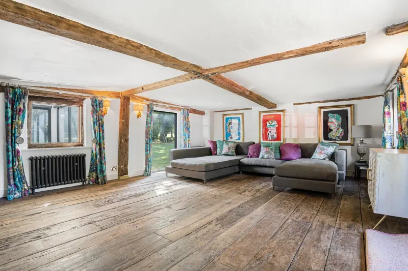 The drawing room with two sofas, beamed ceiling and a wall of paintings