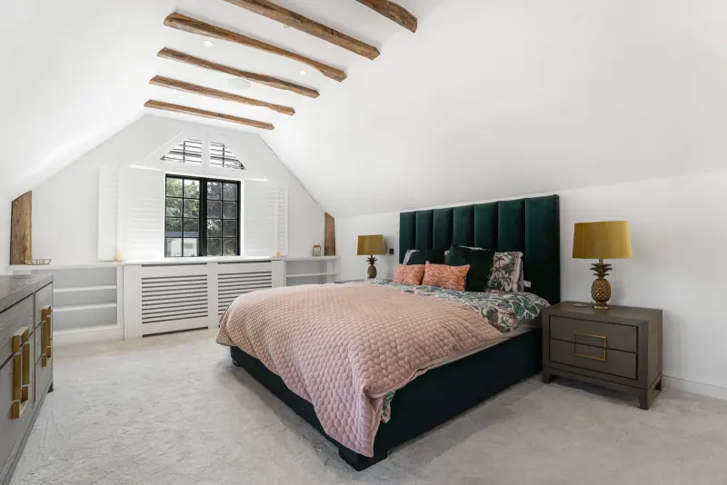 The principal bedroom, vaulted with green-velvet headboard
