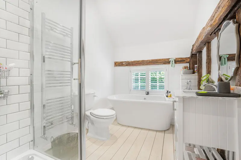 A bathroom with freestanding bath beneath chapel-style windows
