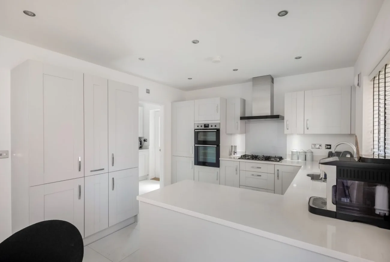Kitchen with quartz island, downlights, integrated appliances.