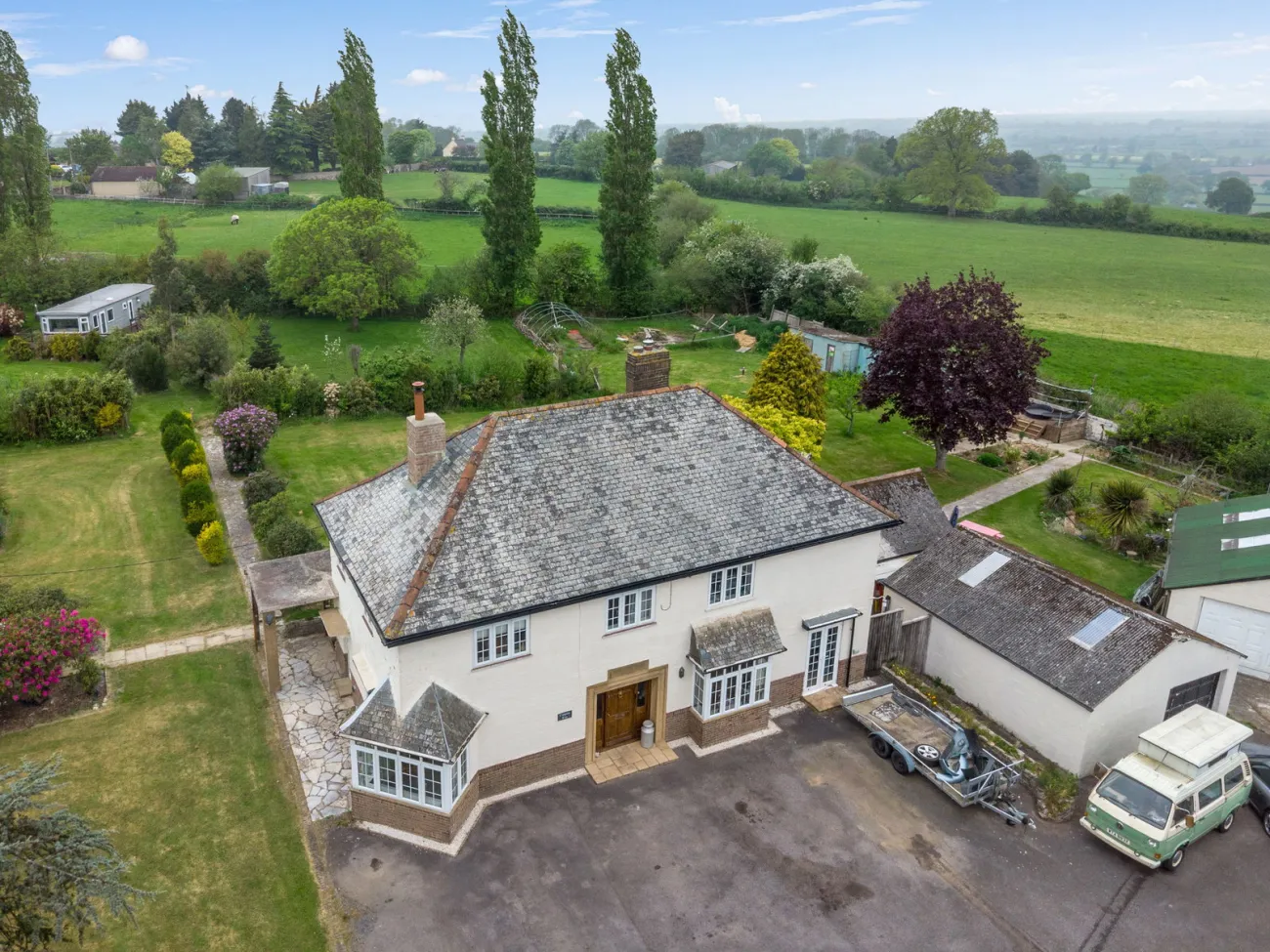 Aerial view across the front of the home showing the sweeping driveway, parking, and the run of the plot to The Retreat.