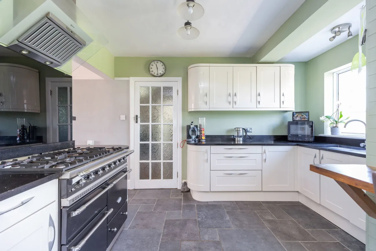 The kitchen with cream shaker cabinetry, a range-style cooker, and a glazed pantry door.
