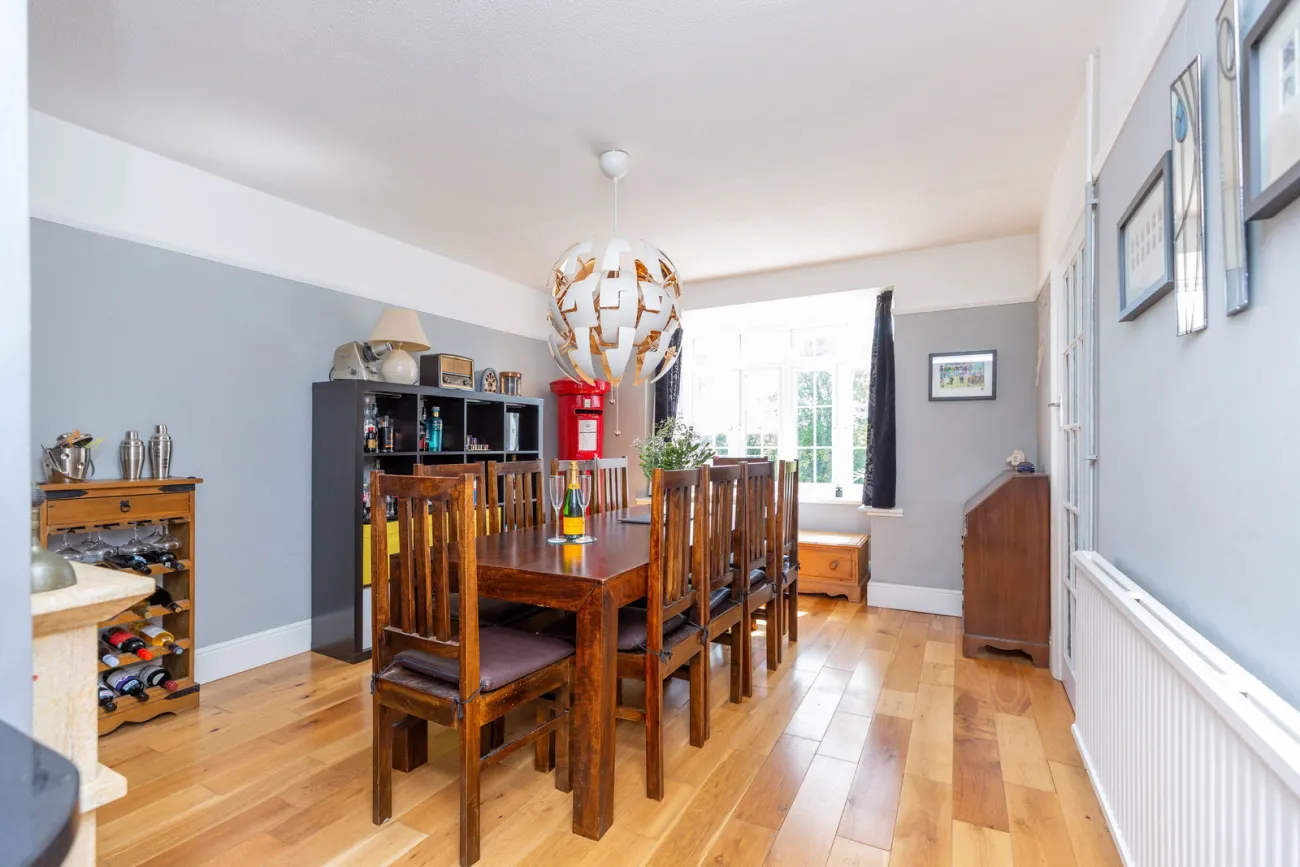 The formal dining room with a wood floor, large family table, and a bay window onto the garden.