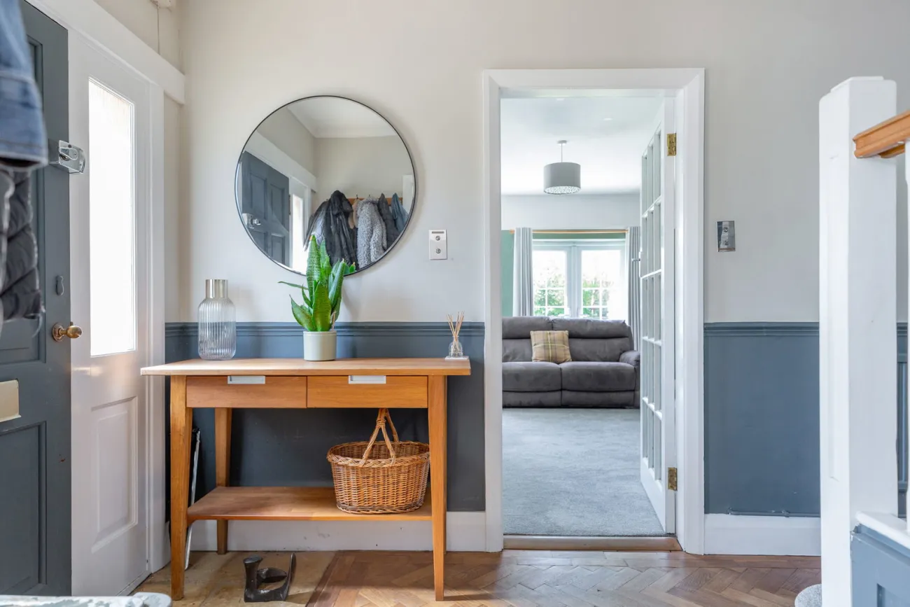 The entrance hall with parquet floor, console table, and a long sightline through to the living room.