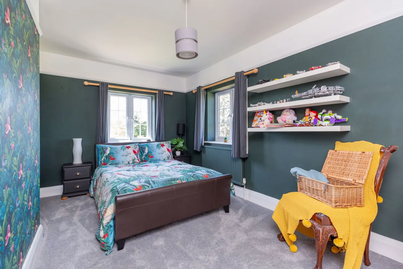 A third bedroom in deep teal with botanical wallpaper and twin garden aspects.