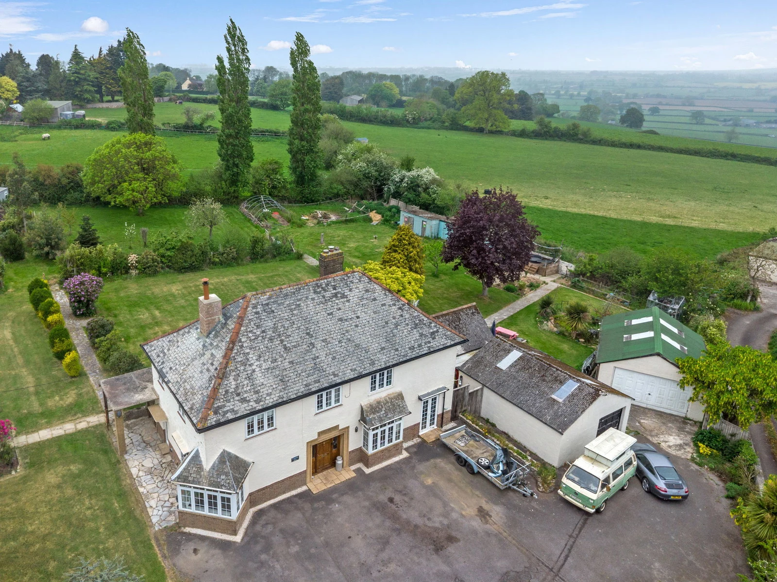 Aerial view of the white-rendered home set within its mature 1.67-acre plot, garden behind, open countryside beyond.