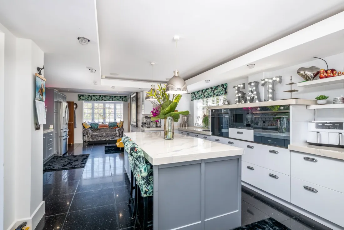 Contemporary kitchen with island, gloss cabinetry and marble-effect surfaces.