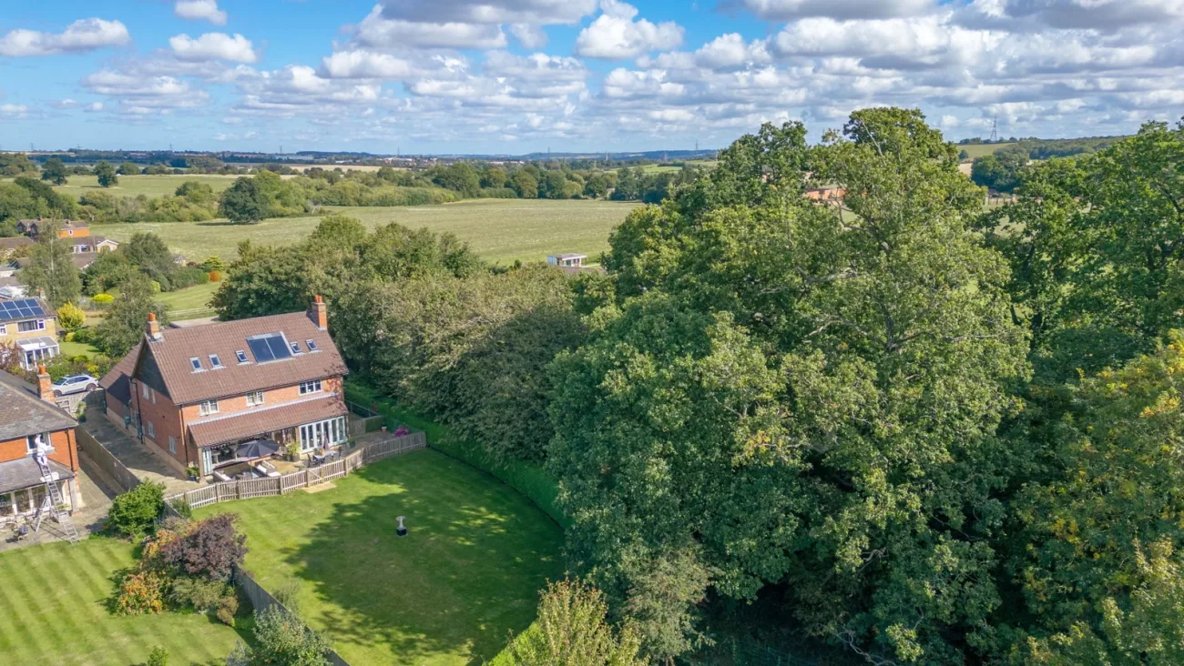 Drone aerial — Woodland View in its village-edge setting.